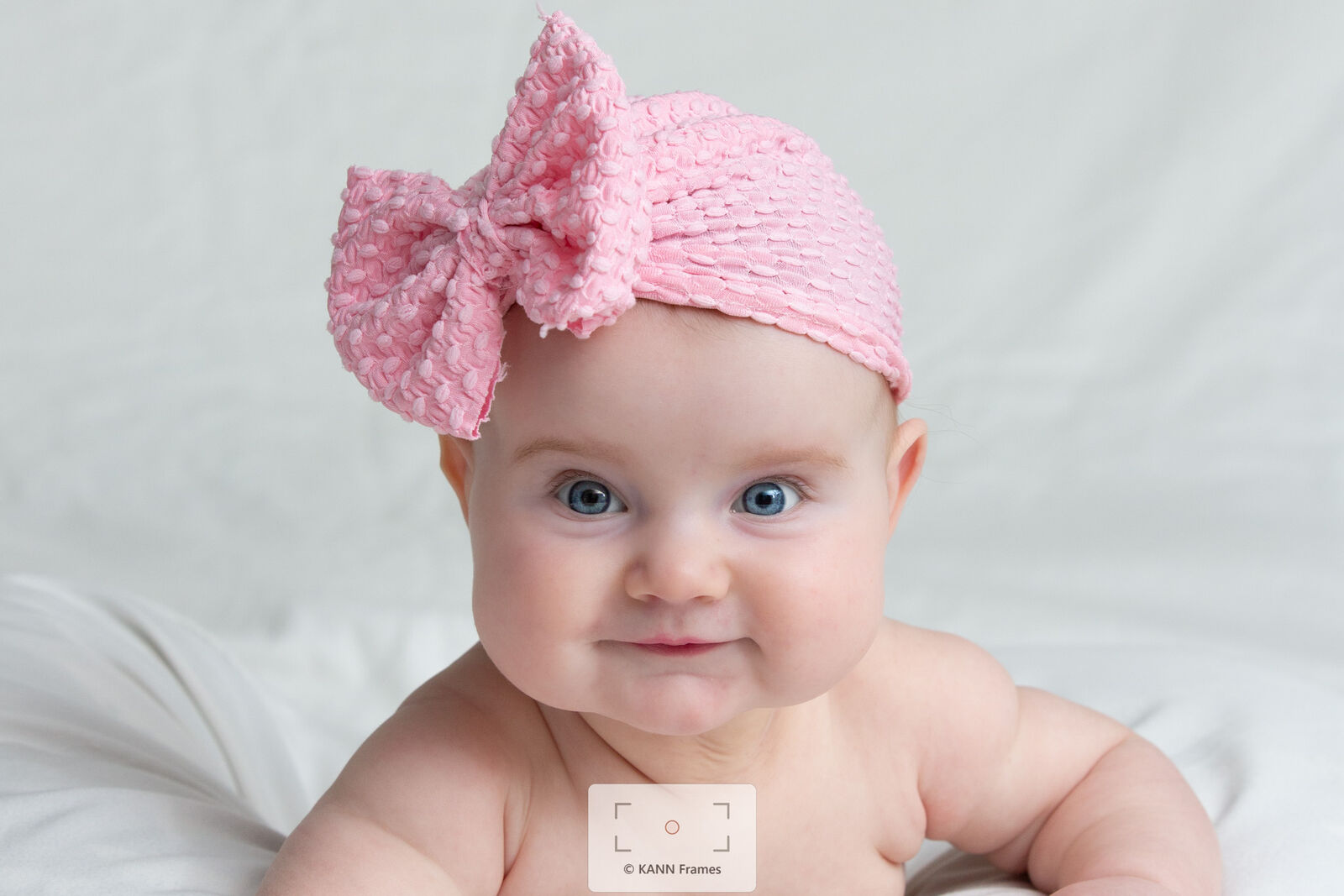 Baby girl in a pink bow headband, studio portrait
