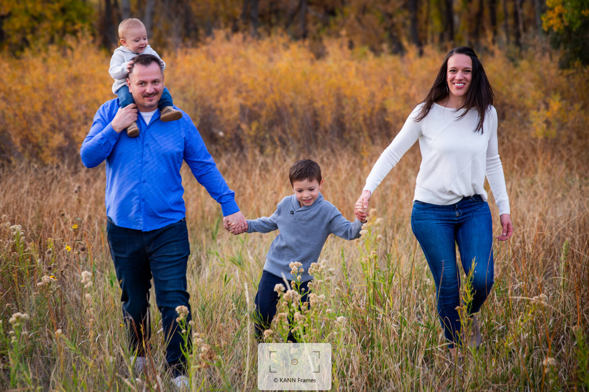 Family of four walking through a golden autumn field