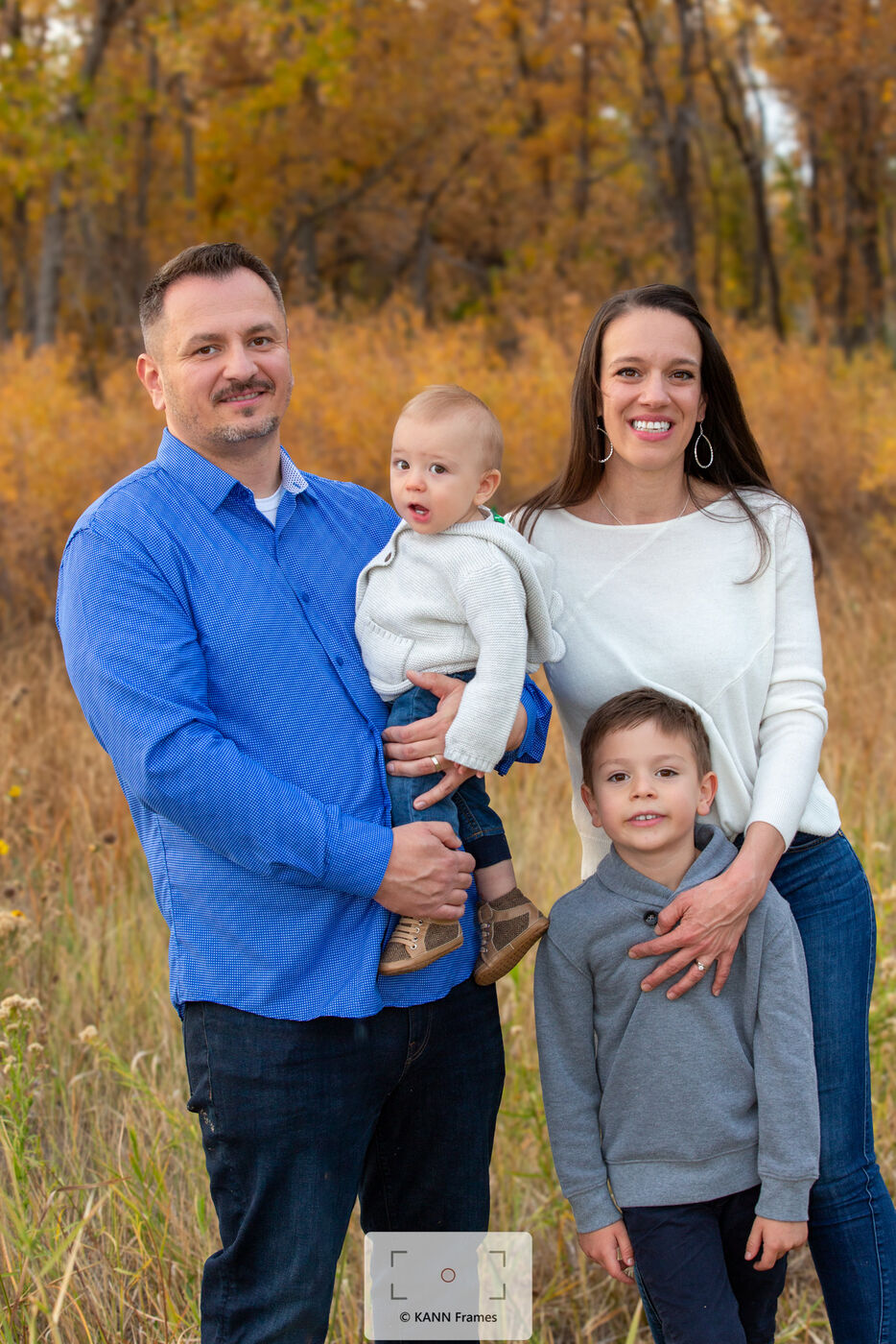 Family of four standing together in an autumn field
