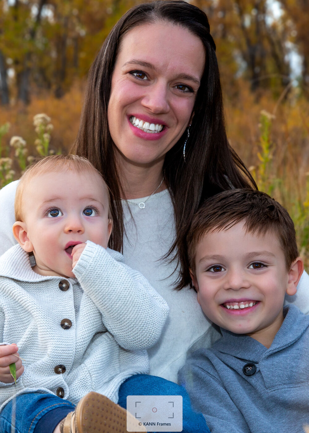 Mother laughing with her two children outdoors in autumn light