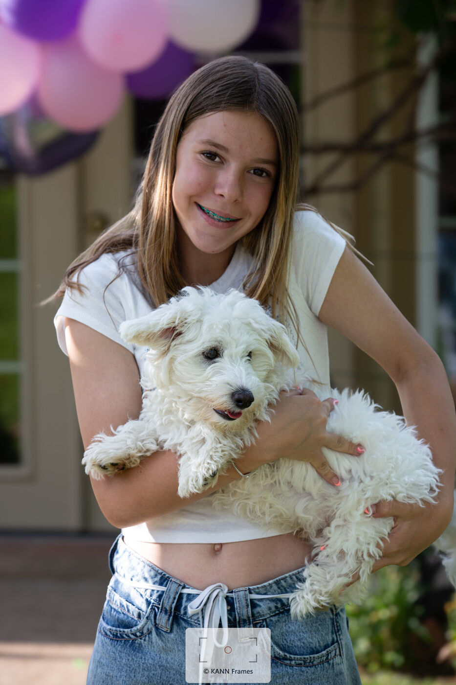 Teen girl holding her fluffy white dog at a birthday party